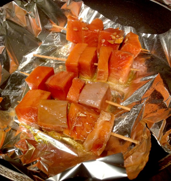 Coloca las brochetas de salmón sobre el papel aluminio y encima el resto de la salsa teriyaki.